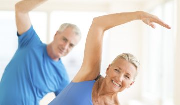 Portrait of smiling senior couple performing stretching exercise at home